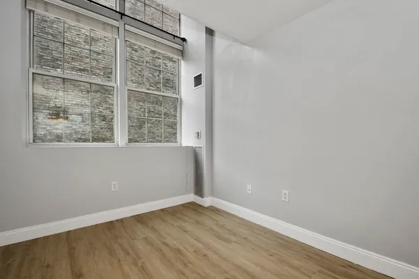 a view of an empty room with wooden floor and a window