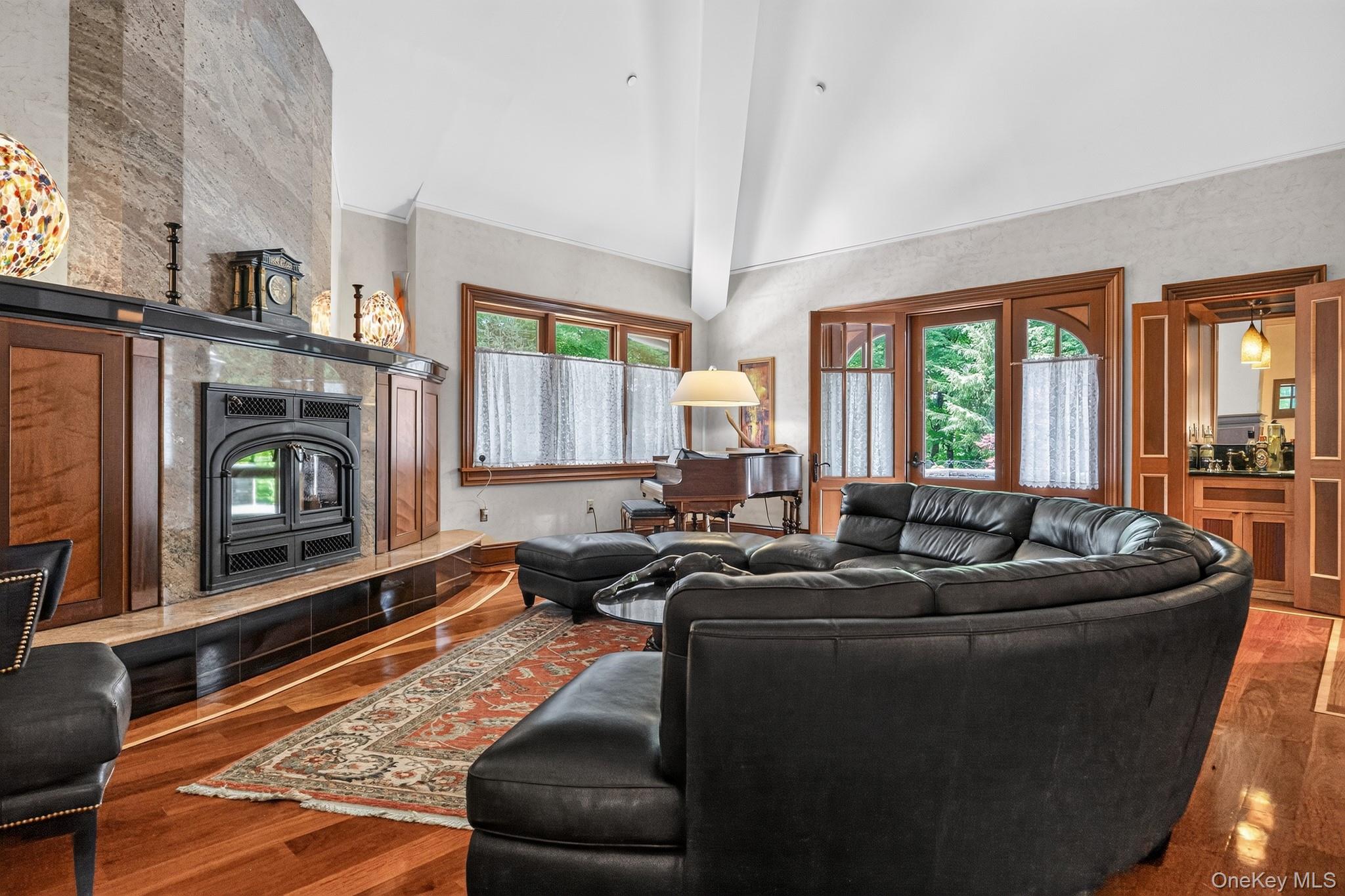 23 Inningwood Road Ossining, NY 10562 - Photo 14 of 50 Spacious living area featuring a prominent fireplace with stone surround and wood mantel, rich wood-finish flooring, vaulted white ceiling, and arched wooden doors