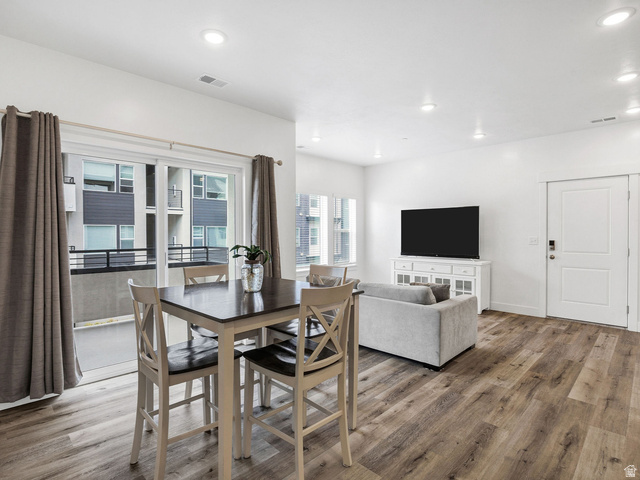 Open concept living area featuring wood-finish flooring, recessed lighting, and a white interior door