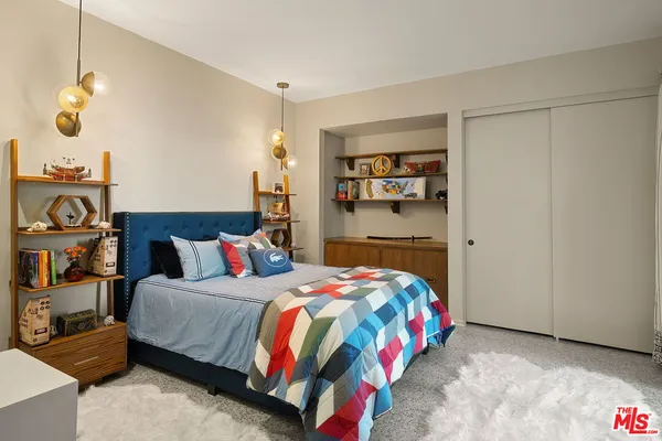 a bedroom with a bed a dresser and book shelf