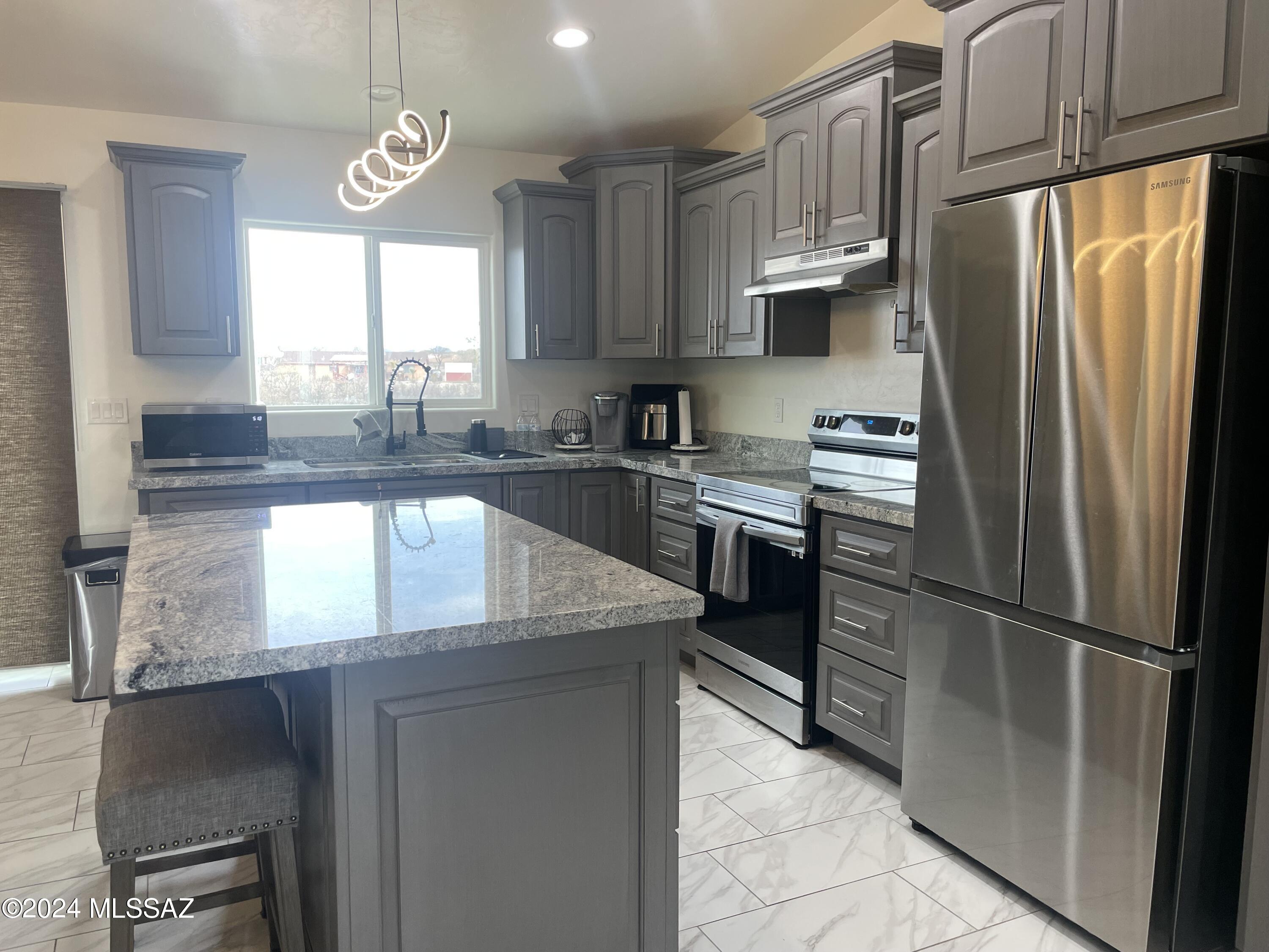 964 Calle Coyote Rio Rico, AZ 85648 - Photo 5 of 16 a kitchen with granite countertop stainless steel appliances a refrigerator microwave and sink