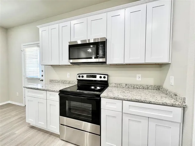 a kitchen with white cabinets and stainless steel appliances