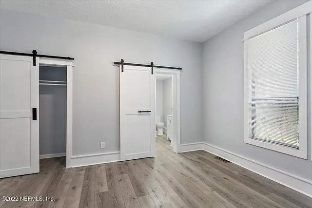a view of an empty room with closet and a window