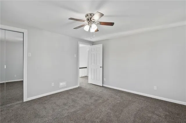 an empty room with closet and a chandelier fan