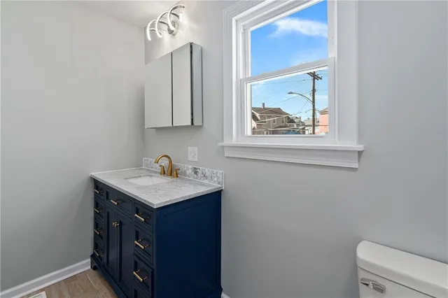 a bathroom with a granite countertop sink a toilet and a window