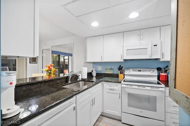 a kitchen with white cabinets and white appliances