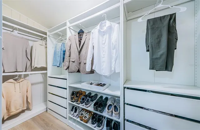 a view of walk in closet with clothes and shoes
