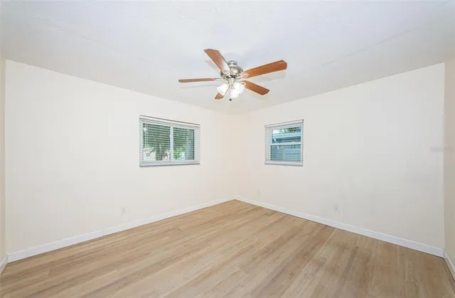 an empty room with wooden floor and ceiling fan