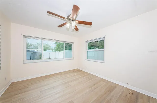 a view of an empty room with wooden floor and a window