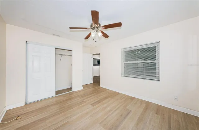 a view of empty room with wooden floor and fan