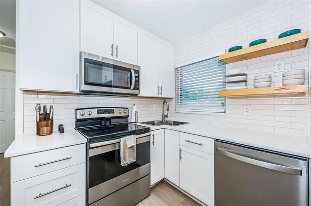 a kitchen with cabinets stainless steel appliances and wooden floor