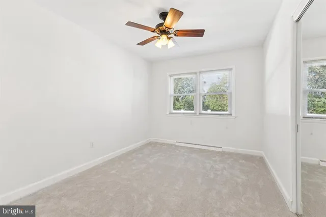 an empty room with a window and a fan