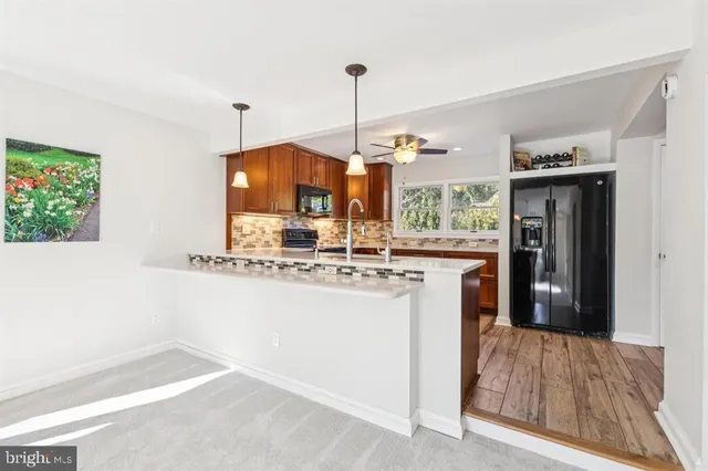 a kitchen with kitchen island granite countertop a refrigerator a oven a stove and a wooden floors