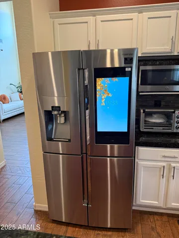 a kitchen with stainless steel appliances granite countertop a refrigerator a stove top oven a sink dishwasher and wooden cabinets with wooden floor