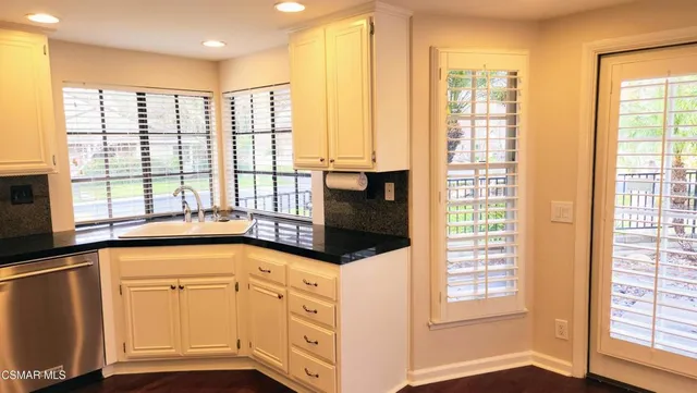a view of a kitchen with stainless steel appliances wooden floor and a large window