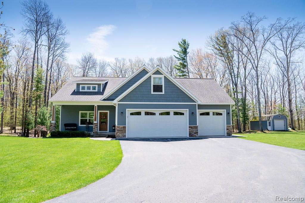 101 Highview Road Traverse City, MI 49696 - Photo 2 of 88 Craftsman-style home featuring a front lawn, a porch, stone siding, asphalt driveway, and an attached garage