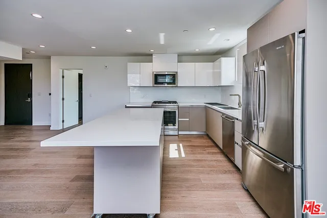 a kitchen with stainless steel appliances granite countertop a refrigerator a sink a stove and oven