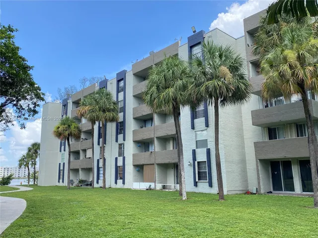 a view of a building with a big yard and large trees