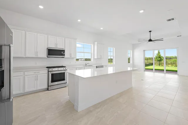 a large kitchen with kitchen island a large counter top space appliances and a sink