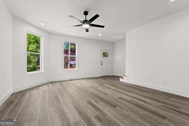 a view of empty room with wooden floor and fan