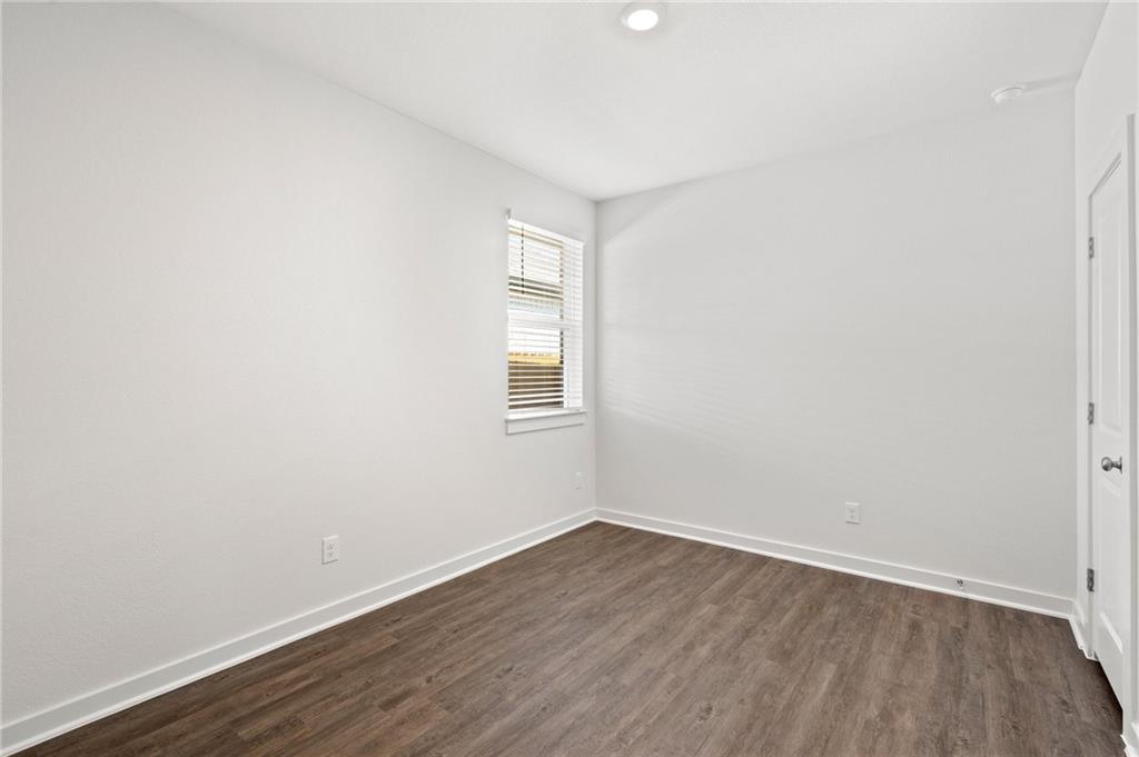 1012 Paddock Lane Georgetown, TX 78626 - Photo 8 of 15 A well-lit bedroom features durable plank flooring and a window for natural light.