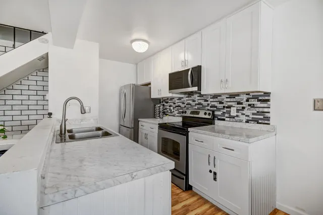 a kitchen with granite countertop a sink stove and refrigerator