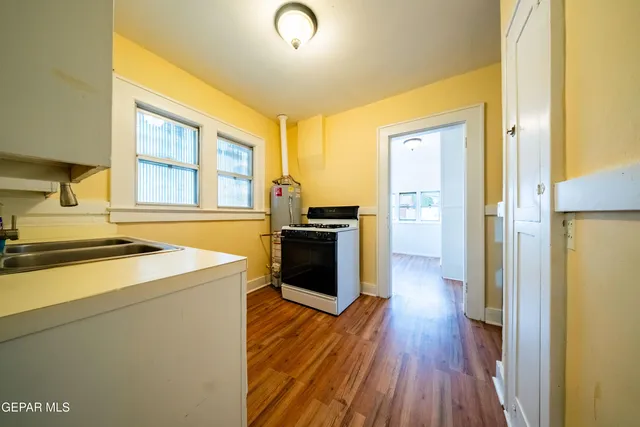 a kitchen with a stove top oven and wooden floor