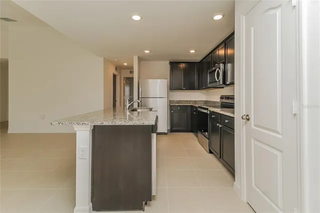 a large kitchen with stainless steel appliances granite countertop a refrigerator and a sink