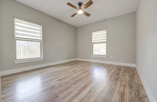a view of empty room with wooden floor and fan