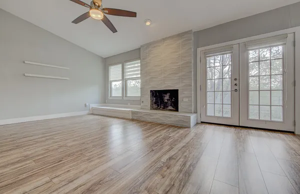 an empty room with wooden floor fireplace and windows