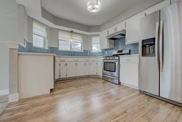 a kitchen with stainless steel appliances granite countertop a stove top oven a sink and a refrigerator