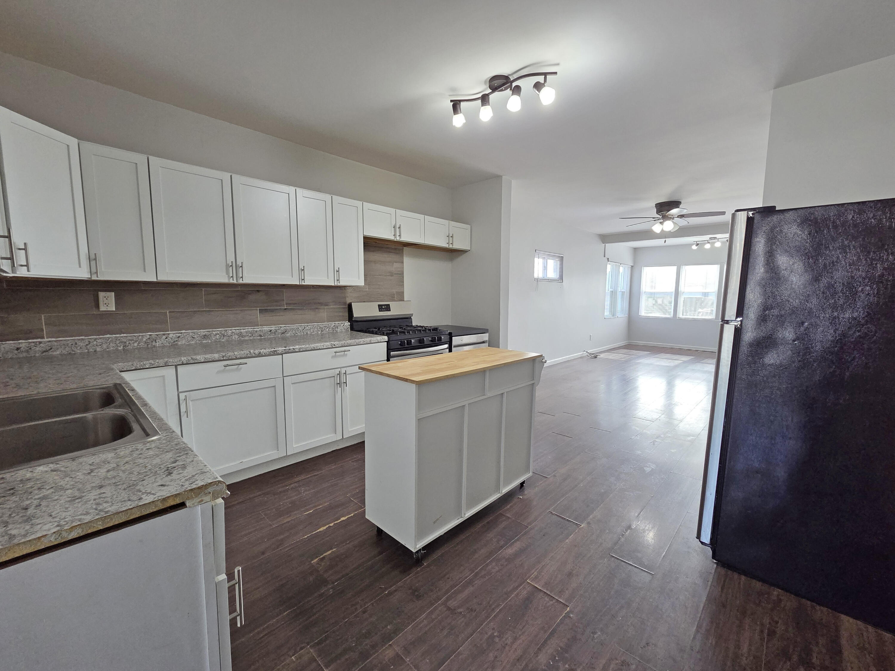 1127 164th Place Hammond, IN 46320 - Photo 14 of 34 a kitchen with granite countertop a stove a sink a refrigerator and white cabinets with wooden floor