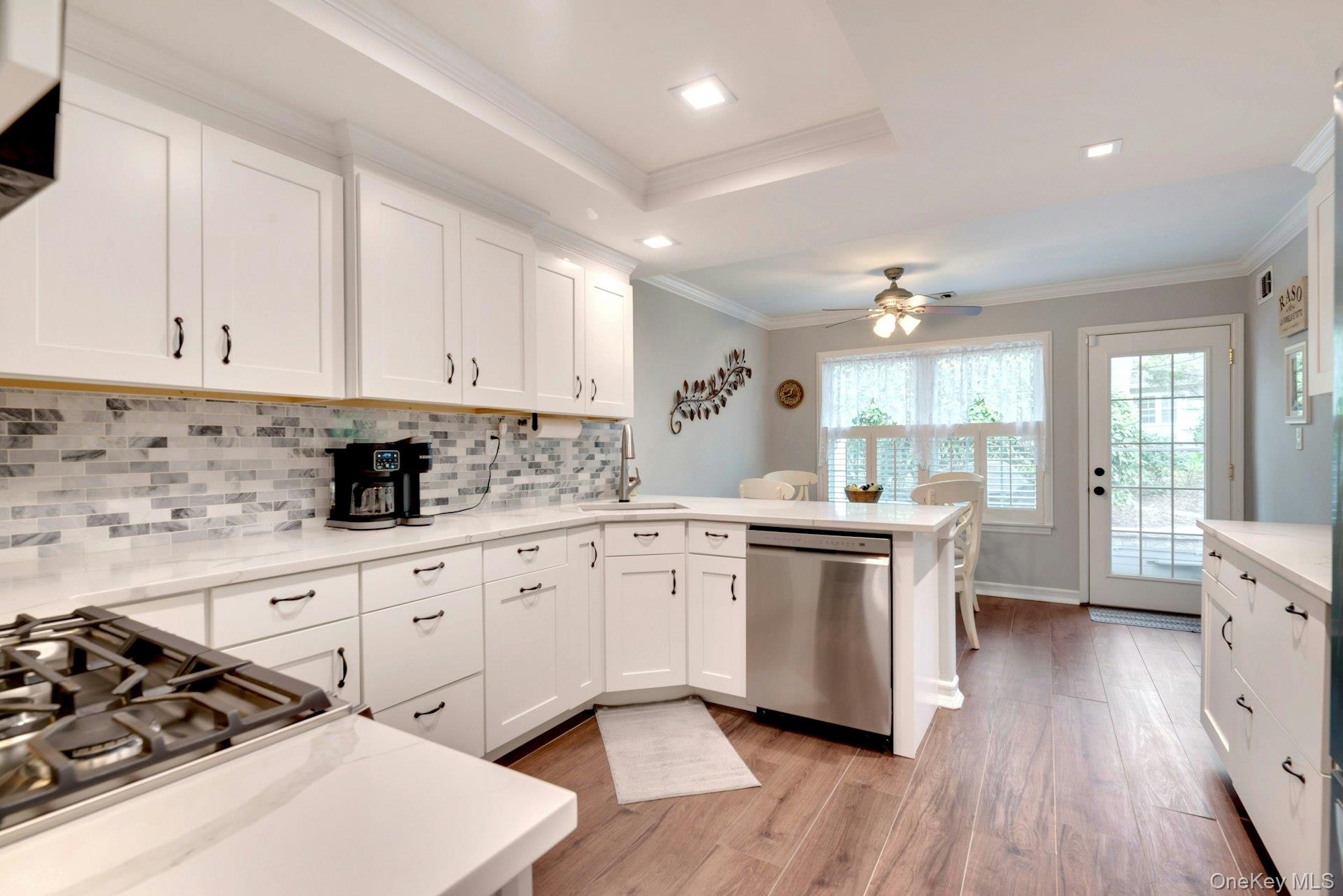 104 Glen Drive Ridge, NY 11961 - Photo 14 of 25 a kitchen with stove a sink and white cabinets with wooden floor