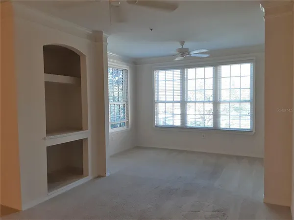 an empty room with chandelier fan and windows