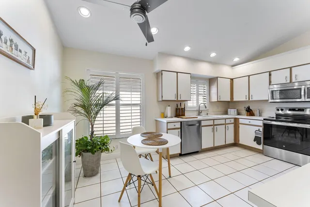 a kitchen with stainless steel appliances kitchen island granite countertop white cabinets a stove a sink and a potted plant