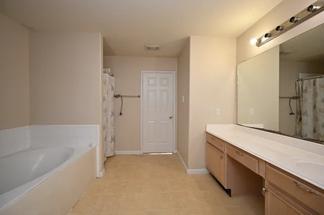 a spacious bathroom with a tub sink shower and mirror