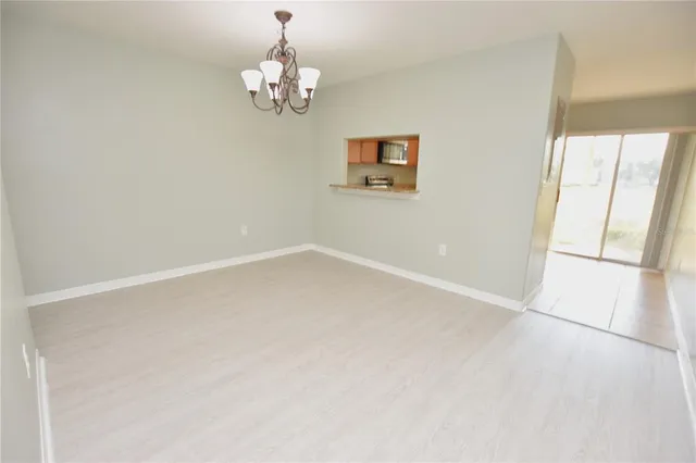 an empty room with a chandelier fan and windows