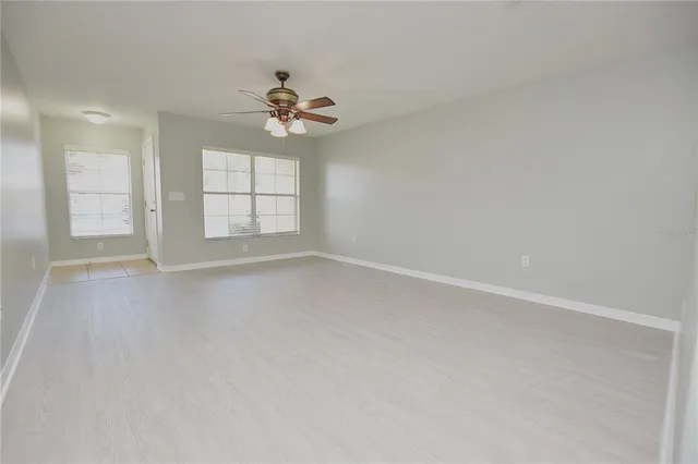 an empty room with windows and ceiling fan