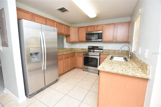 a kitchen with stainless steel appliances granite countertop a refrigerator sink stove microwave and cabinets
