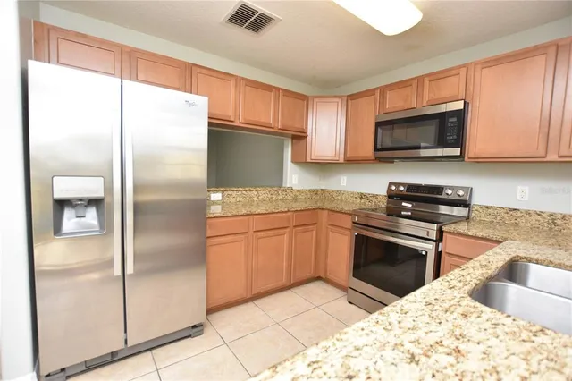 a kitchen with granite countertop a refrigerator and a sink