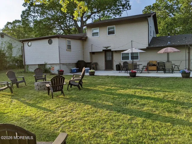 a view of a house with patio chairs and a fire pit