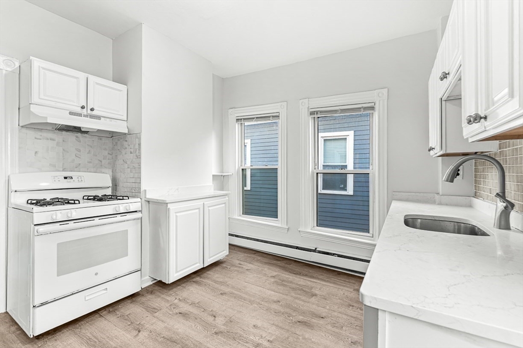 22 Royal Street Boston, MA 02134 - Photo 11 of 42 a kitchen with granite countertop white cabinets and white appliances