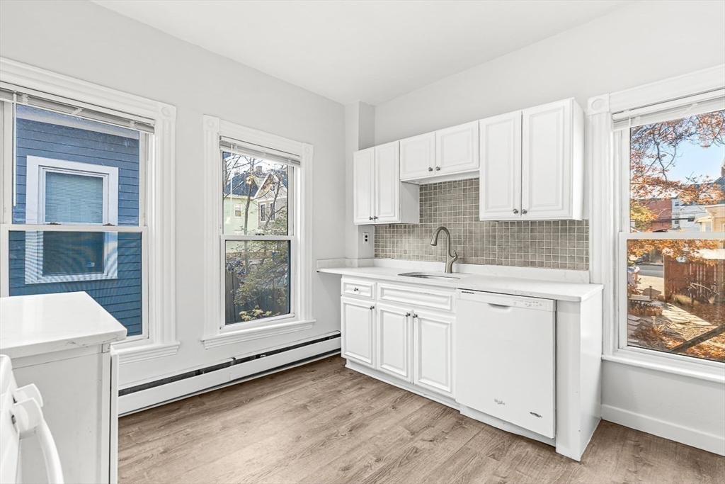 22 Royal Street Boston, MA 02134 - Photo 12 of 42 a kitchen with stainless steel appliances granite countertop a stove a sink and a refrigerator with white cabinets