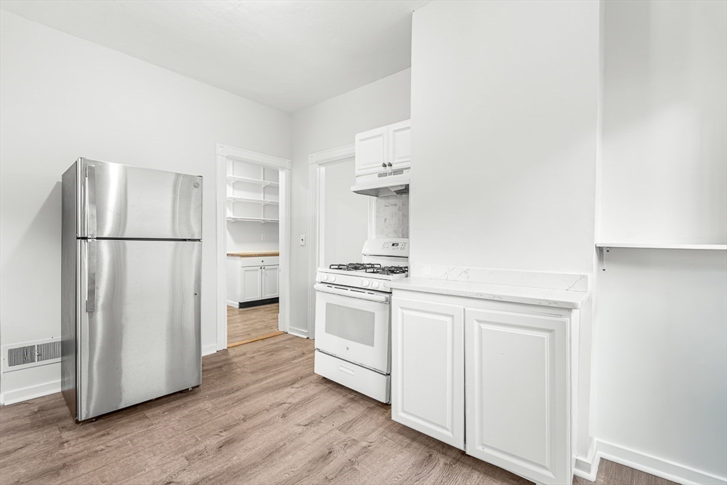 22 Royal Street Boston, MA 02134 - Photo 13 of 42 a kitchen with a refrigerator stove and wooden floor