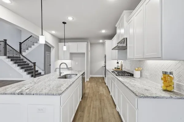 a kitchen with granite countertop stainless steel appliances a sink a stove and cabinets