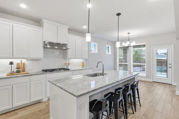 a kitchen with stainless steel appliances granite countertop a sink a stove and a wooden floor