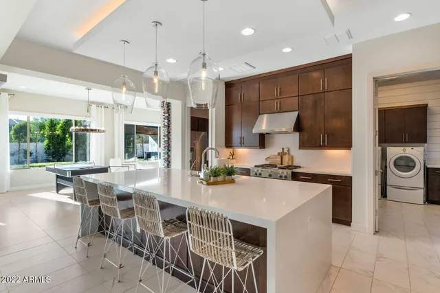 a kitchen with stainless steel appliances a stove a sink a microwave a dining table and chairs
