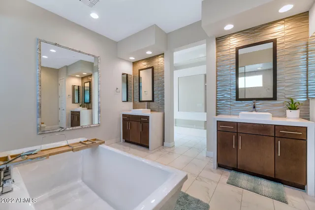 a spacious bathroom with a tub sink and mirror