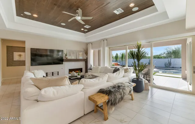 a living room with furniture a flat screen tv and a floor to ceiling window