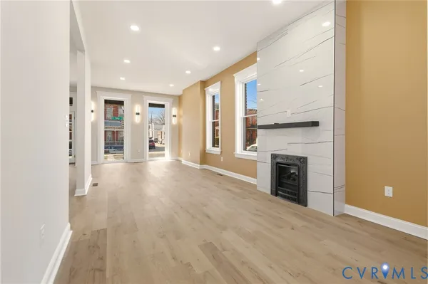 a view of an empty room with wooden floor and a fireplace